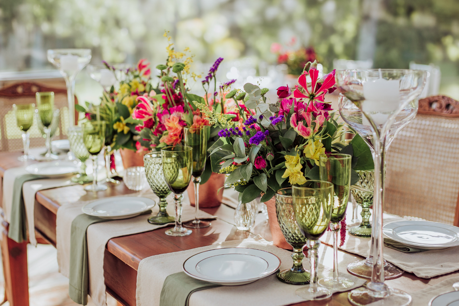 Mesa de recepção com arranjos florais coloridos e taças verdes
