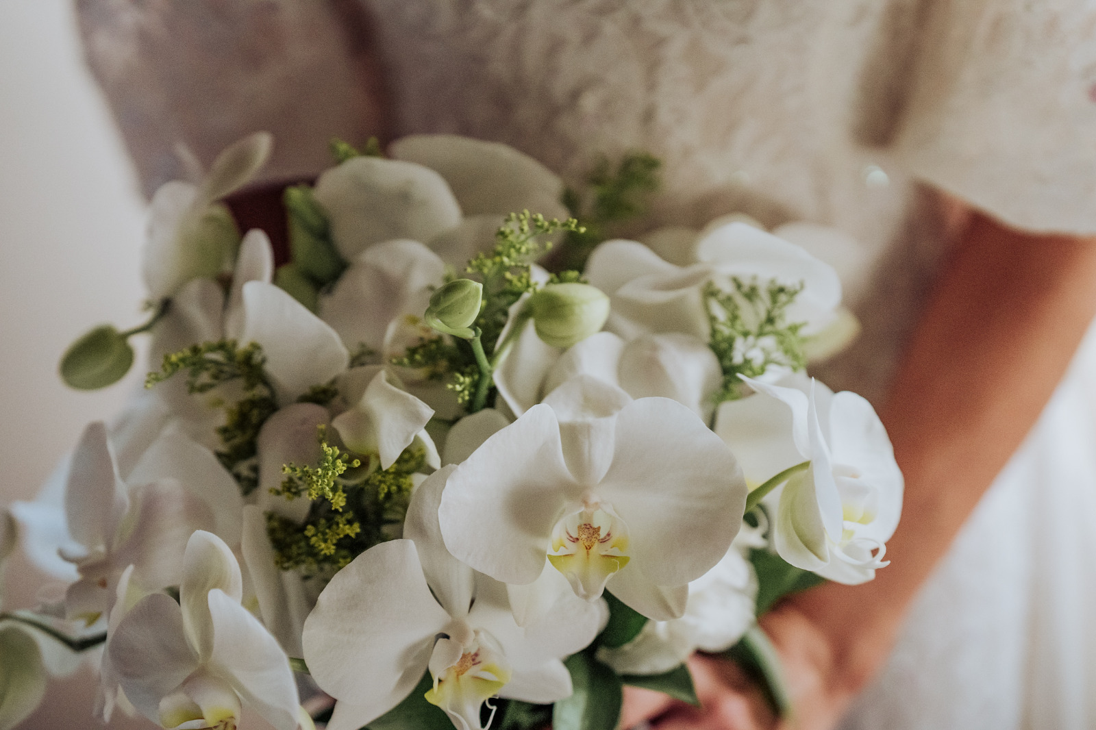 Buquê de orquídeas brancas nas mãos da noiva